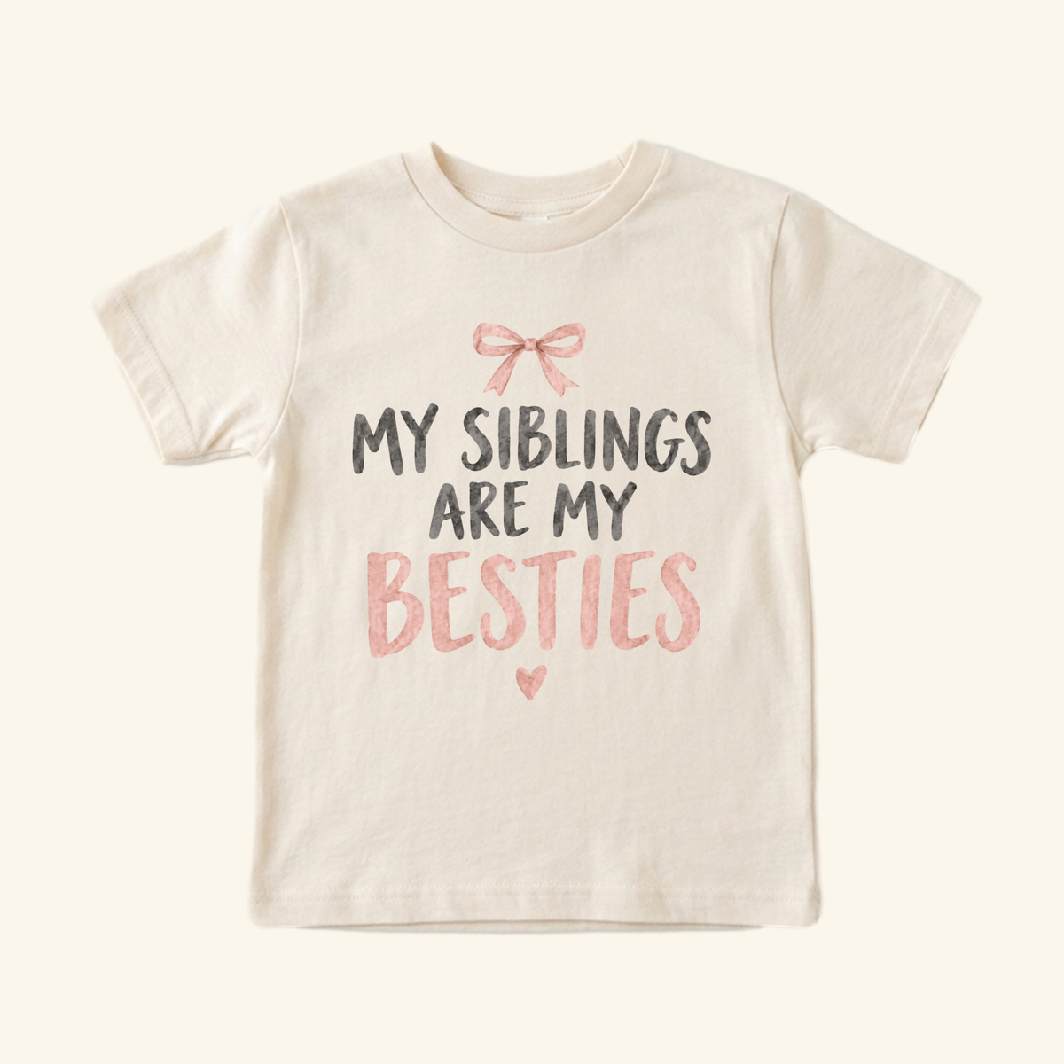 Cream Toodleroos My Siblings Are My Besties Toddler Shirt – Pink Bow Sibling Tee featuring a pink bow, the text My siblings are my besties in black and pink, and a small heart below.
