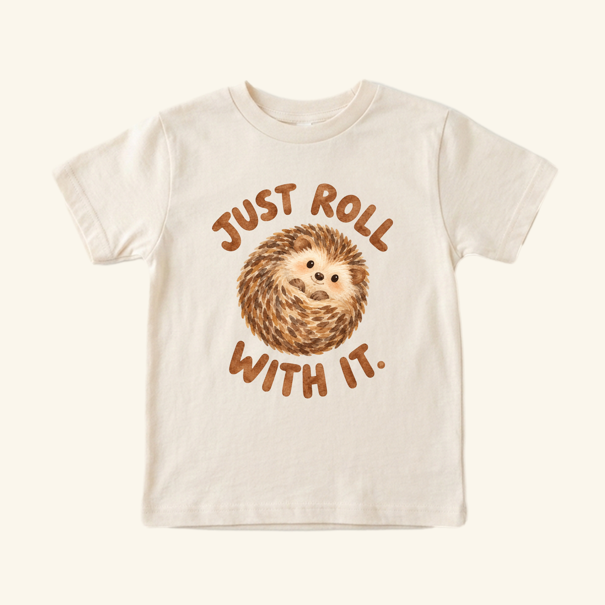 Cream-colored Just Roll With It Toddler Shirt – Cute Hedgehog Tee featuring a watercolor illustration of a curled-up hedgehog and the text Just roll with it.