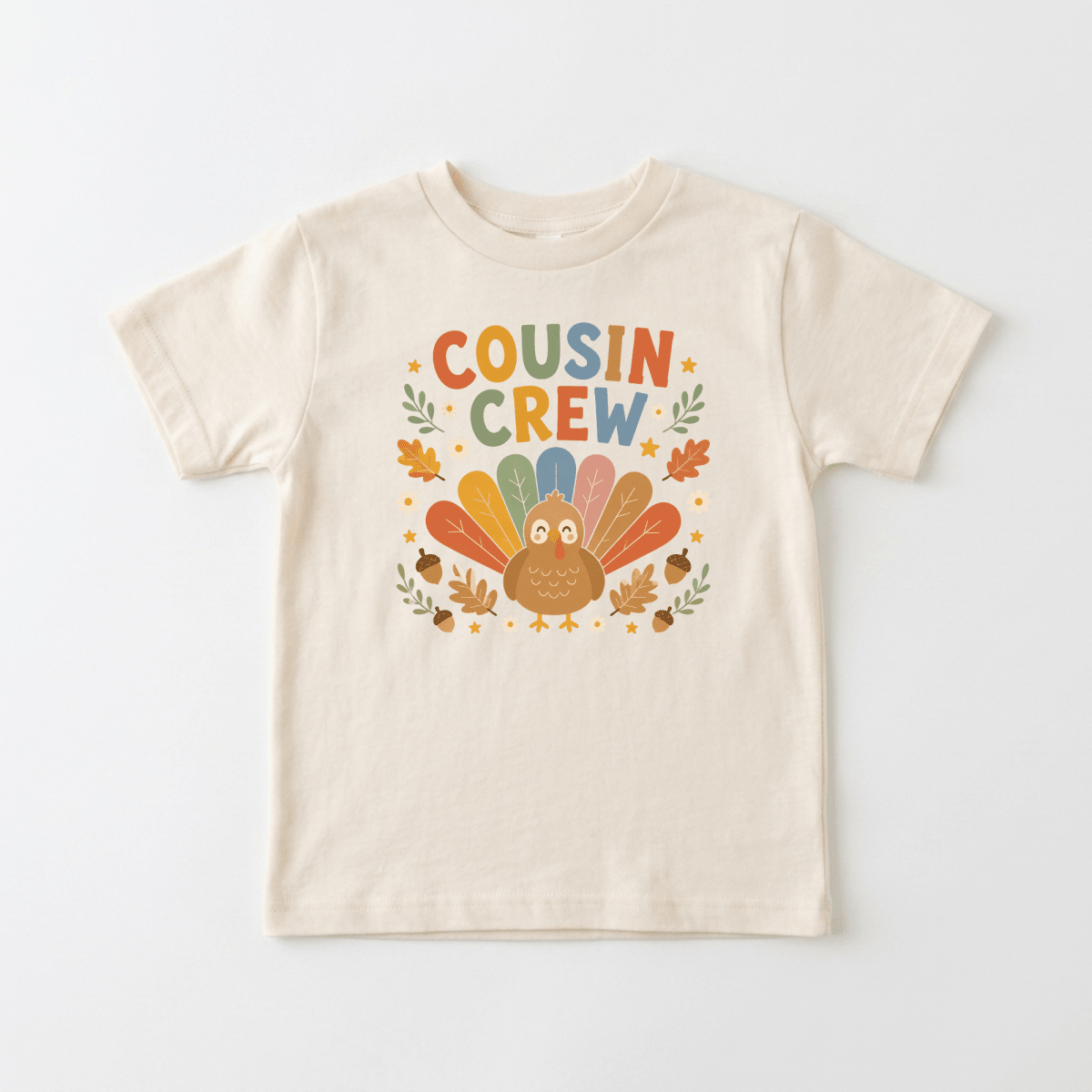 Dress your little one in festive style with the Toodleroos Thanksgiving Cousin Shirt – Cousin Crew Turkey Toddler Tee. This cream-colored shirt showcases a vibrant cartoon turkey surrounded by autumn leaves, with “Cousin Crew” displayed in bold, multicolored letters above the playful design—making it the perfect choice for Thanksgiving family gatherings!.