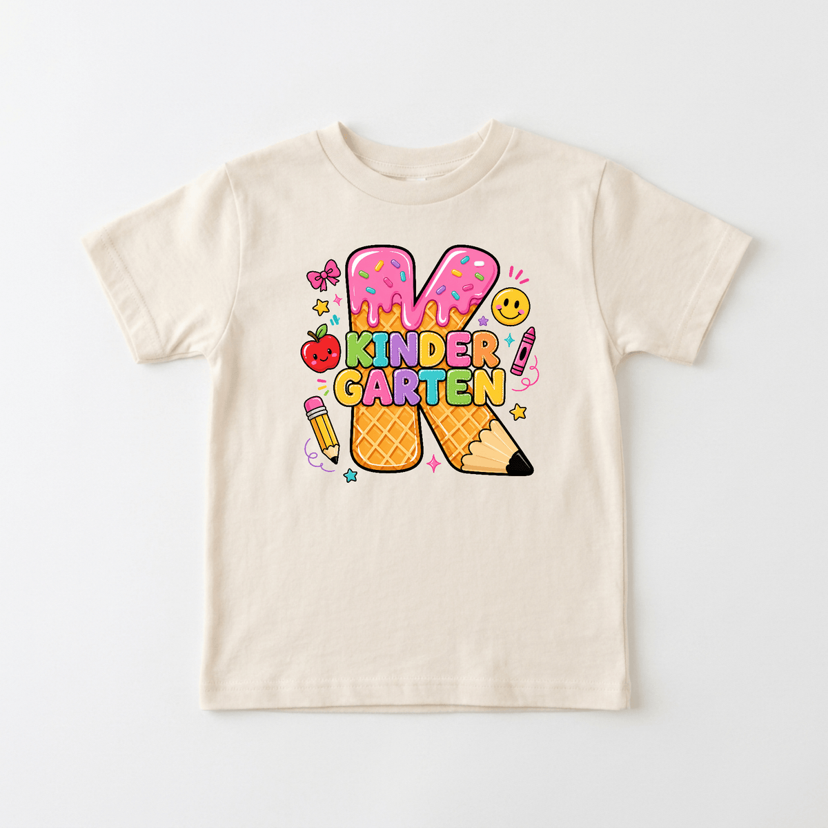 Introducing the Kindergarten Youth Girls Shirt – Ice Cream K Tee by Toodleroos: a cream-colored t-shirt featuring vibrant “Kindergarten” text in playful donut- and pencil-themed letters, surrounded by adorable illustrations like a smiley face, apple, butterfly, and pink pencil—perfect for kindergarten or as a fun first day of school outfit!.