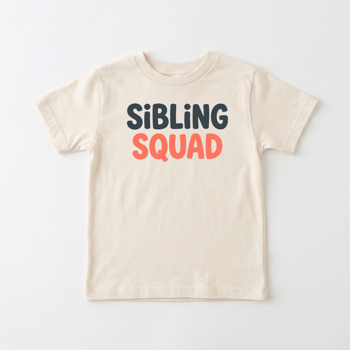 The Sibling Squad Toddler Shirt – Matching Sibling Tee by Toodleroos features a beige design with “SIBLING” in dark gray and “SQUAD” in coral pink printed on the front. Perfect for siblings, this modern and playful tee is an ideal way to celebrate sibling bonds with style.