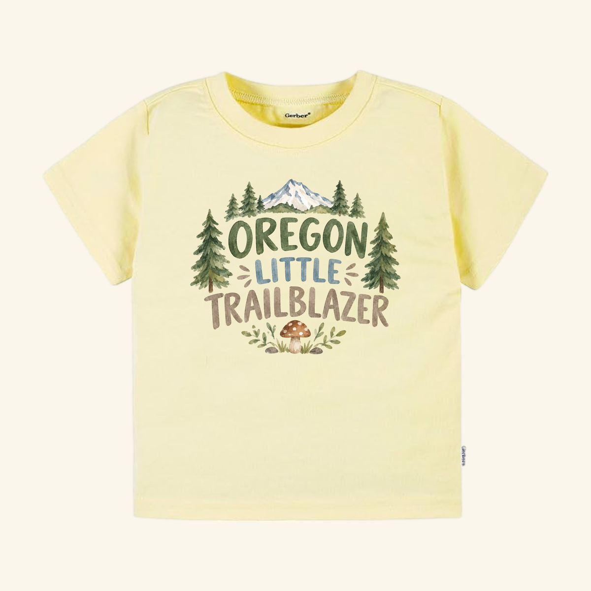 Pale yellow Toodleroos Oregon Toddler Shirt – Little Trailblazer Mountain Forest Tee featuring a graphic of a mountain, pine trees, and a mushroom with the text Little Trailblazer.