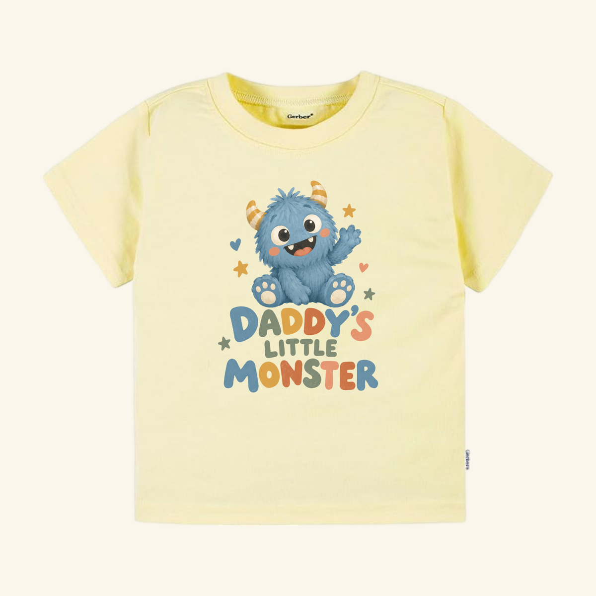 Pale yellow Daddy’s Little Monster Toddler Shirt featuring a blue monster illustration and the text DADDYS LITTLE MONSTER.