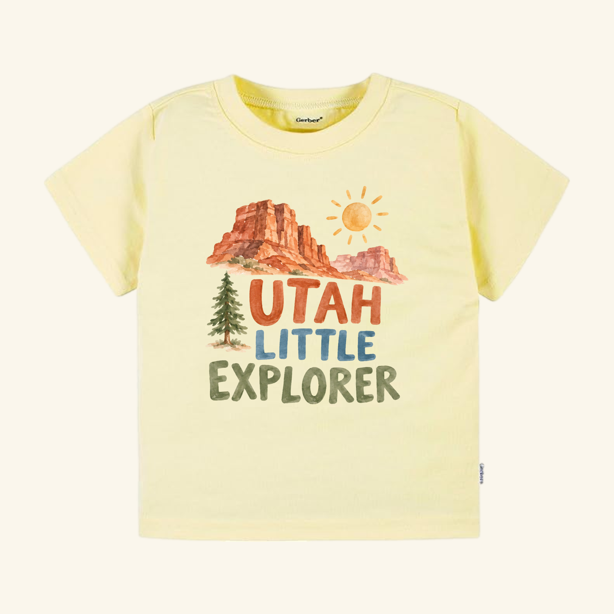 Pale yellow Utah Toddler Shirt – Little Explorer Red Rock Desert Tee featuring a watercolor illustration of red rock desert formations, a pine tree, a sun, and the text UTAH LITTLE EXPLORER.