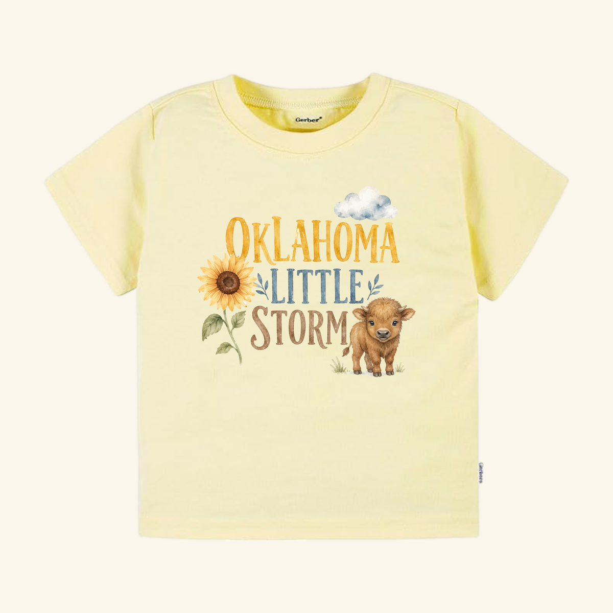 Light yellow Oklahoma Toddler Shirt – Little Storm Sunflower & Baby Bison Tee featuring a graphic of a sunflower, a small bison, a cloud, and the text OKLAHOMA LITTLE STORM.