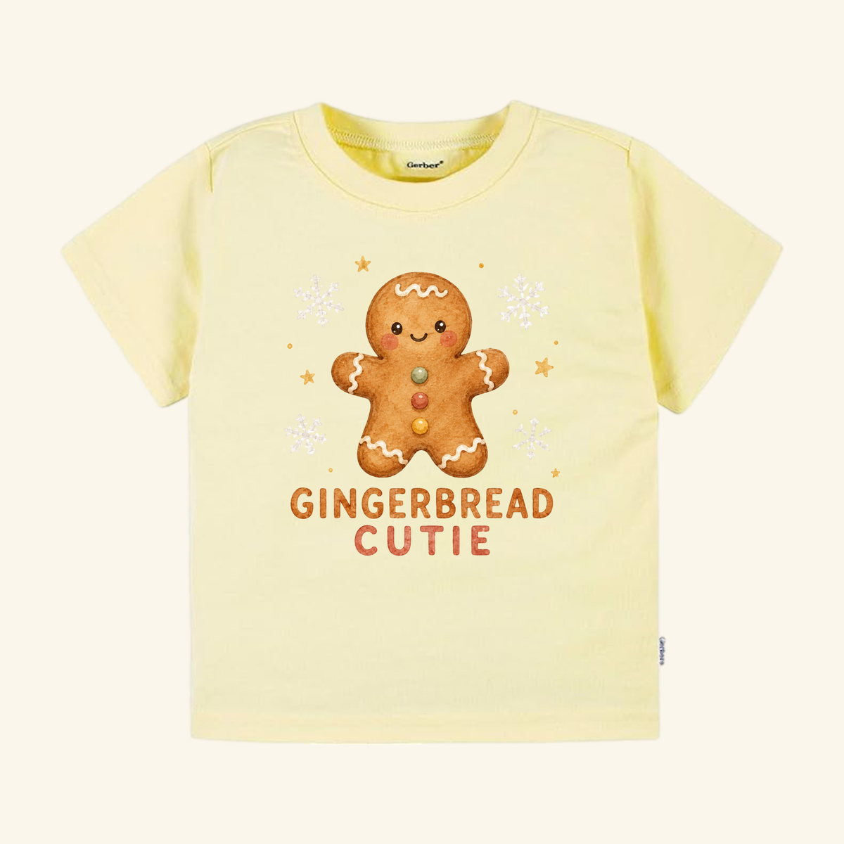 Pale yellow Gingerbread Cutie Toddler Shirt – Cute Christmas Gingerbread Man Tee featuring a smiling gingerbread man, snowflakes, stars, and the text GINGERBREAD CUTIE.