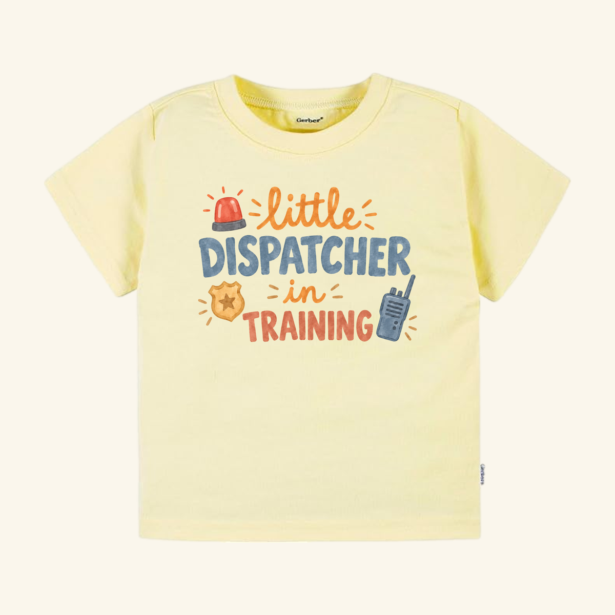 Light yellow Little Dispatcher in Training Toddler Shirt with a graphic featuring a siren, a badge, and a walkie-talkie.