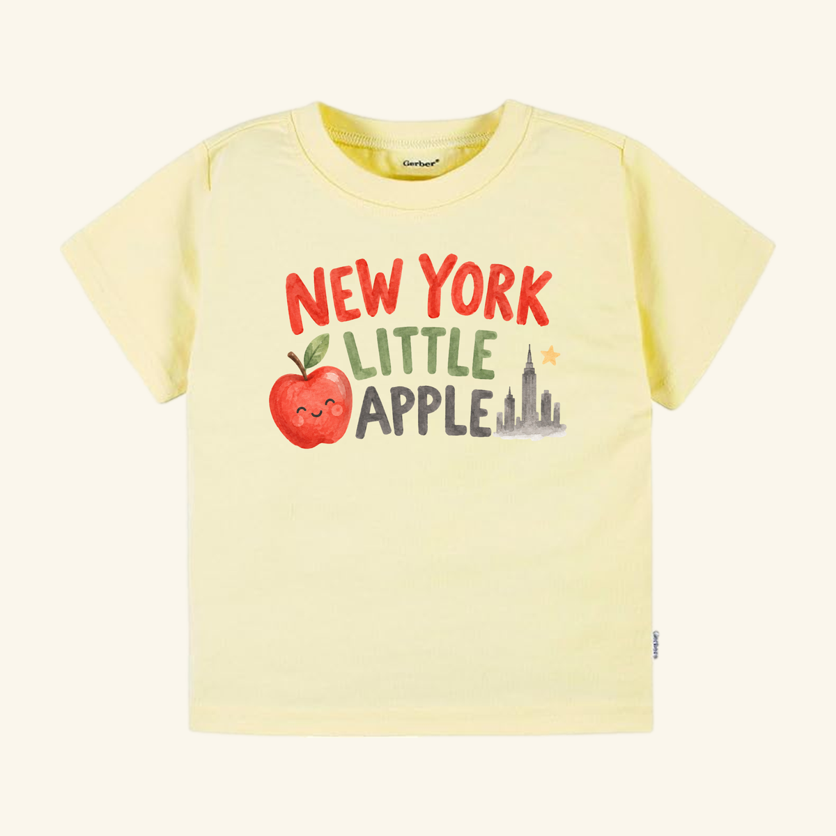 Pale yellow New York Toddler Shirt – Little Apple Skyline Watercolor Tee featuring a watercolor graphic of a smiling apple and a New York City skyline with the text NEW YORK LITTLE APPLE.
