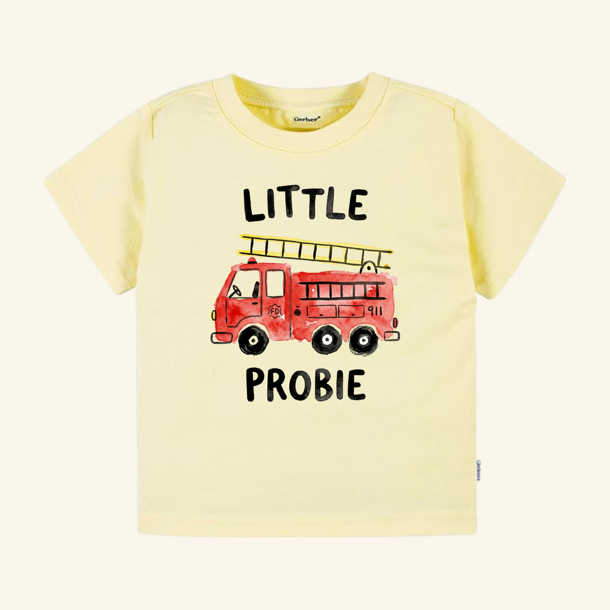 Pale yellow short-sleeved Little Probie Toddler Shirt – Firefighter Fire Truck Tee featuring a watercolor illustration of a red fire truck and the text LITTLE PROBIE.