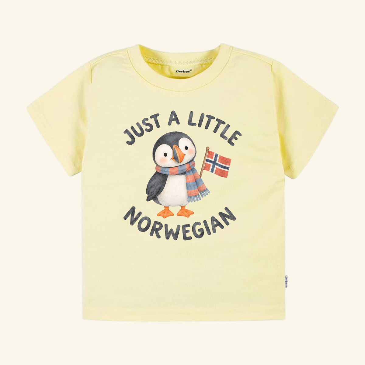 Just a Little Norwegian Toddler Shirt – Cute Puffin Norway Flag Tee in pale yellow, featuring a watercolor puffin wearing a striped scarf and holding a Norwegian flag with the text Just a little Norwegian printed above and below the bird.