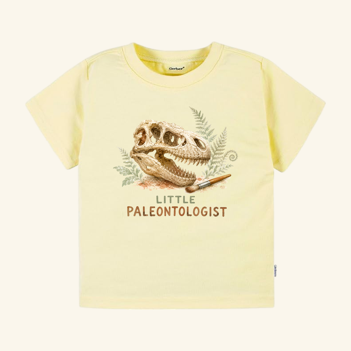 Pale yellow Little Paleontologist Toddler Shirt – T. Rex Fossil Dinosaur Tee featuring a Tyrannosaurus rex skull, a paintbrush, and fern leaves with the text LITTLE PALEONTOLOGIST.