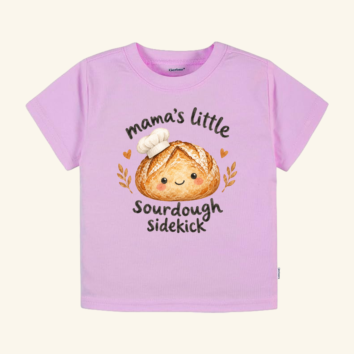 Light pink Toodleroos Mama’s Little Sourdough Sidekick Toddler Shirt featuring a graphic of a smiling sourdough loaf wearing a chef’s hat and the text, mama’s little sourdough sidekick.