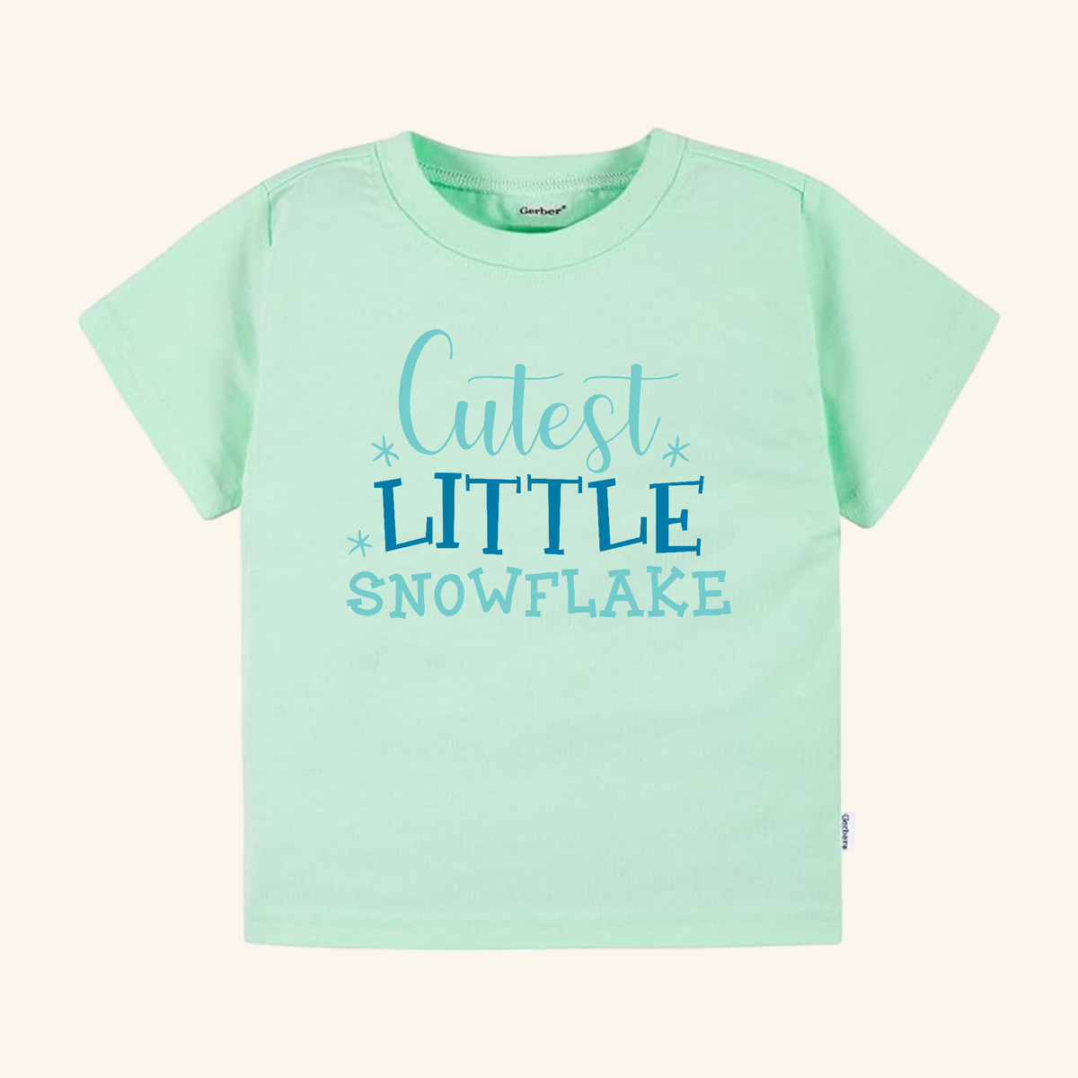 Light green short-sleeved Winter Toddler Shirt – Cutest Little Snowflake Tee featuring the text Cutest LITTLE SNOWFLAKE in blue, surrounded by small snowflake icons.