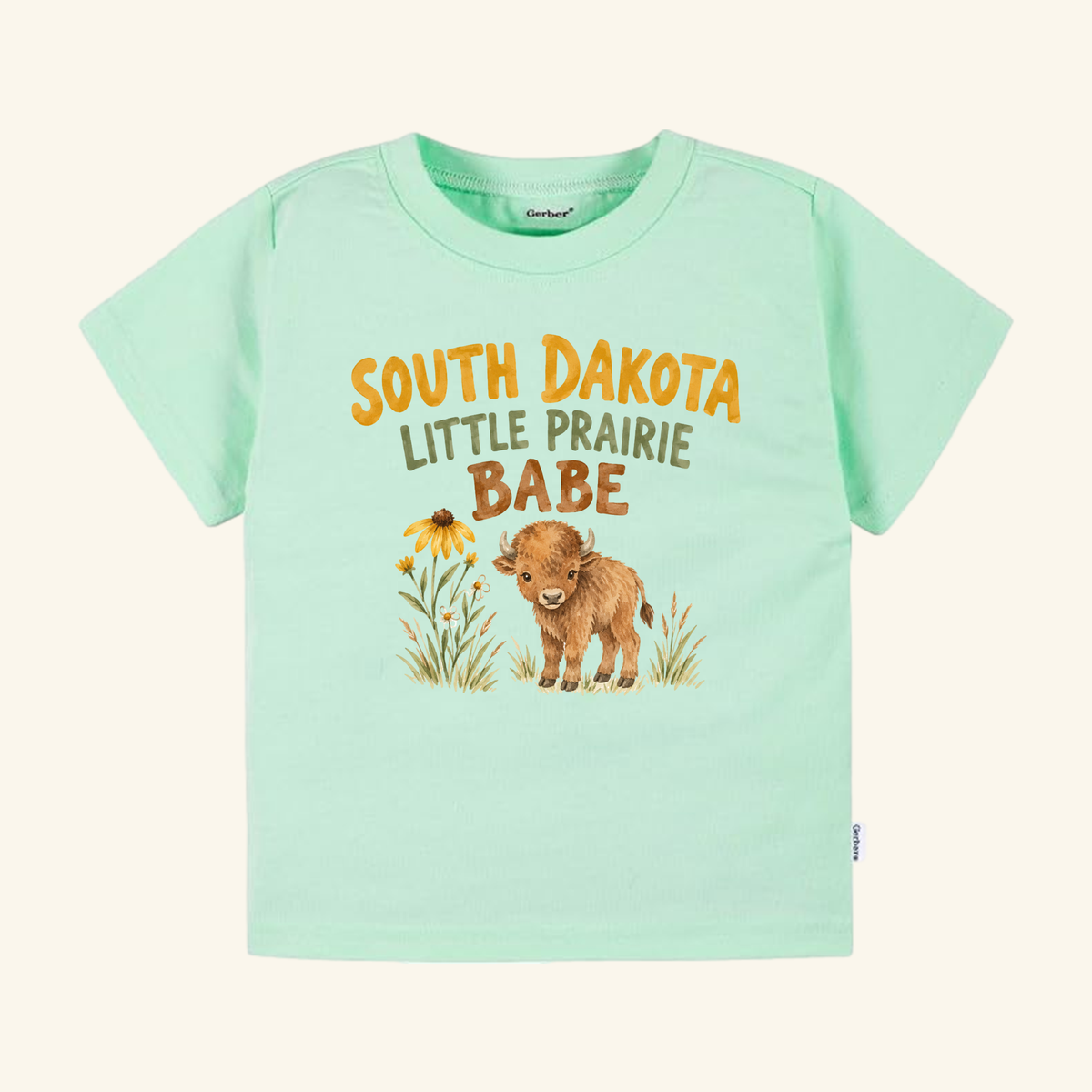 Light green South Dakota Toddler Shirt – Little Prairie Babe Buffalo Tee featuring an illustration of a baby buffalo and flowers with the text South Dakota Little Prairie Babe.