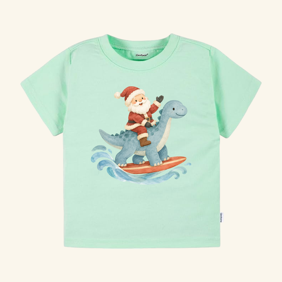 Light green Toodleroos Santa Surfing Dinosaur Toddler Shirt – Christmas Beach Tee featuring an illustration of Santa Claus riding a blue dinosaur on a surfboard.