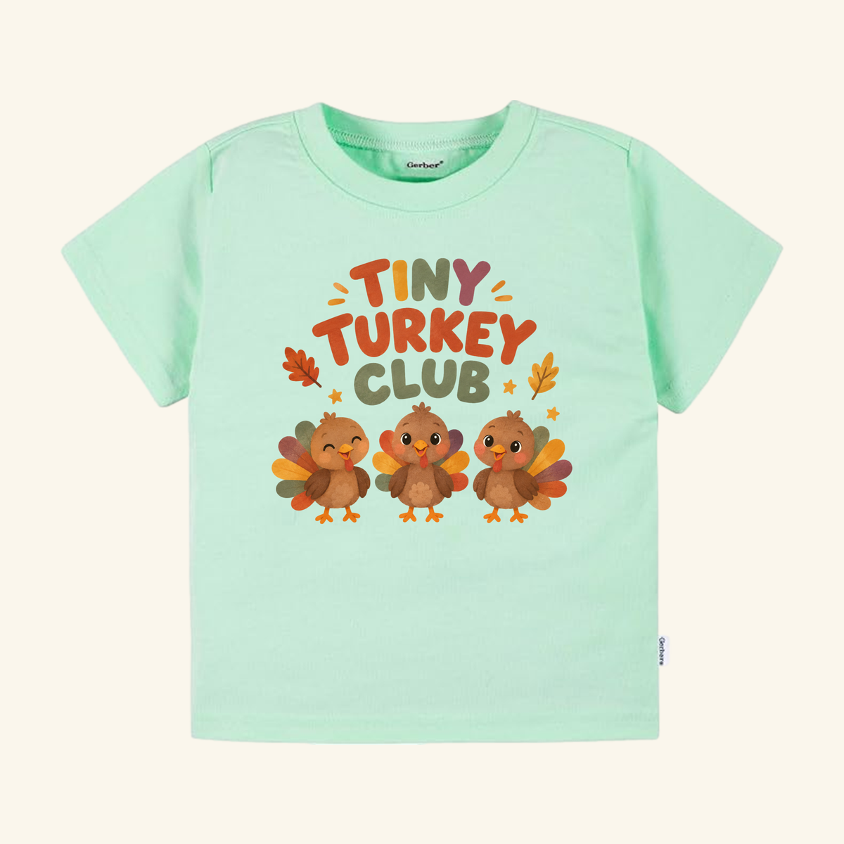 Mint green short-sleeve Tiny Turkey Club Toddler Thanksgiving Shirt featuring a graphic of three turkeys and text with autumn leaf accents.