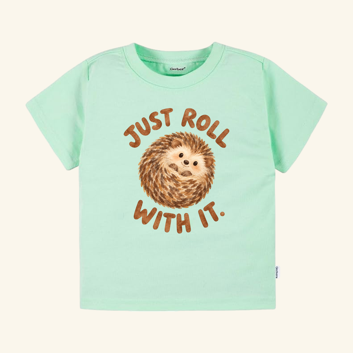 Mint green Toodleroos Just Roll With It Toddler Shirt – Cute Hedgehog Tee featuring a brown illustration of a curled-up hedgehog and the text Just Roll With It.