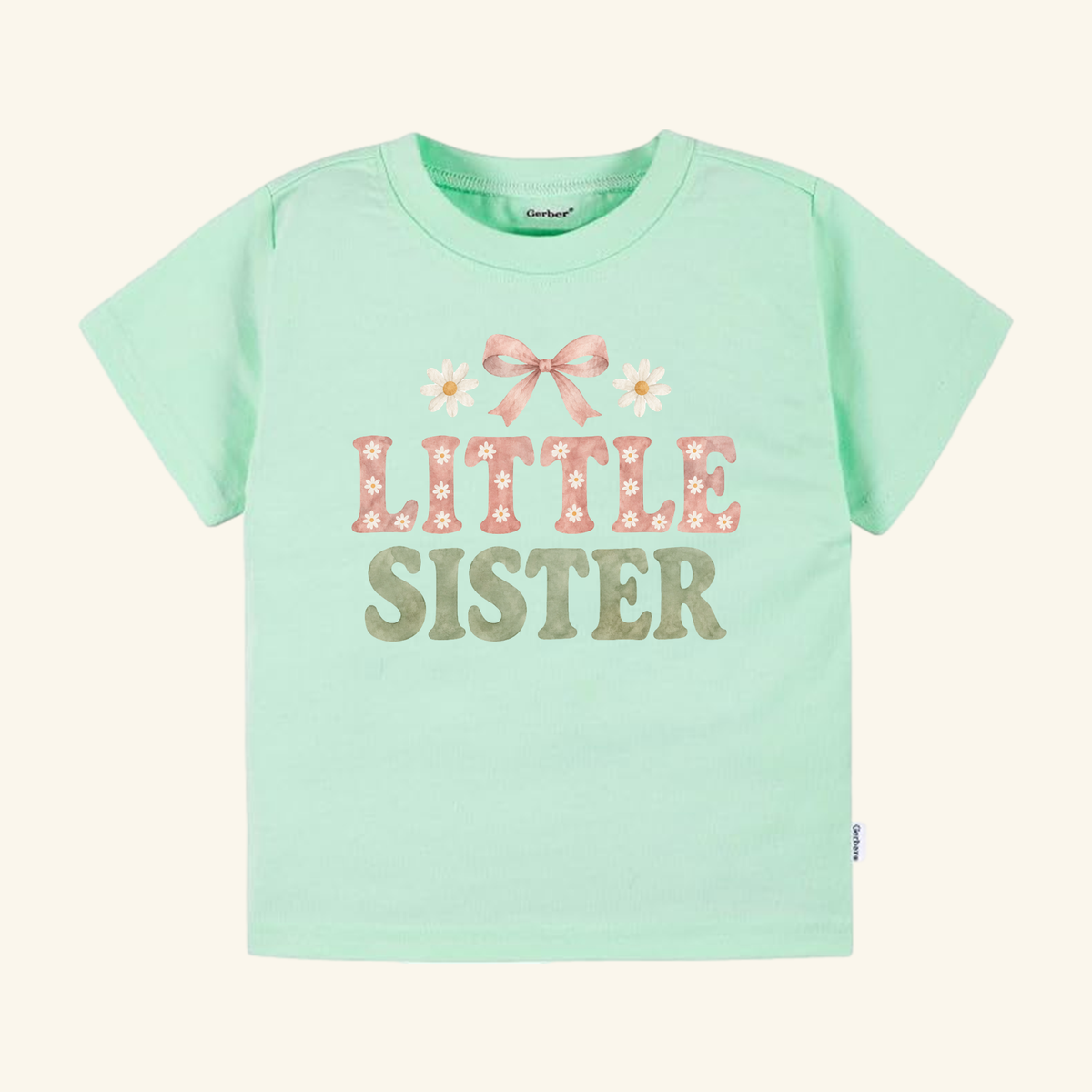 Light green Little Sister Toddler Shirt – Daisy Bow Sibling Tee featuring a pink bow, two daisies, and the text LITTLE SISTER printed on the front.