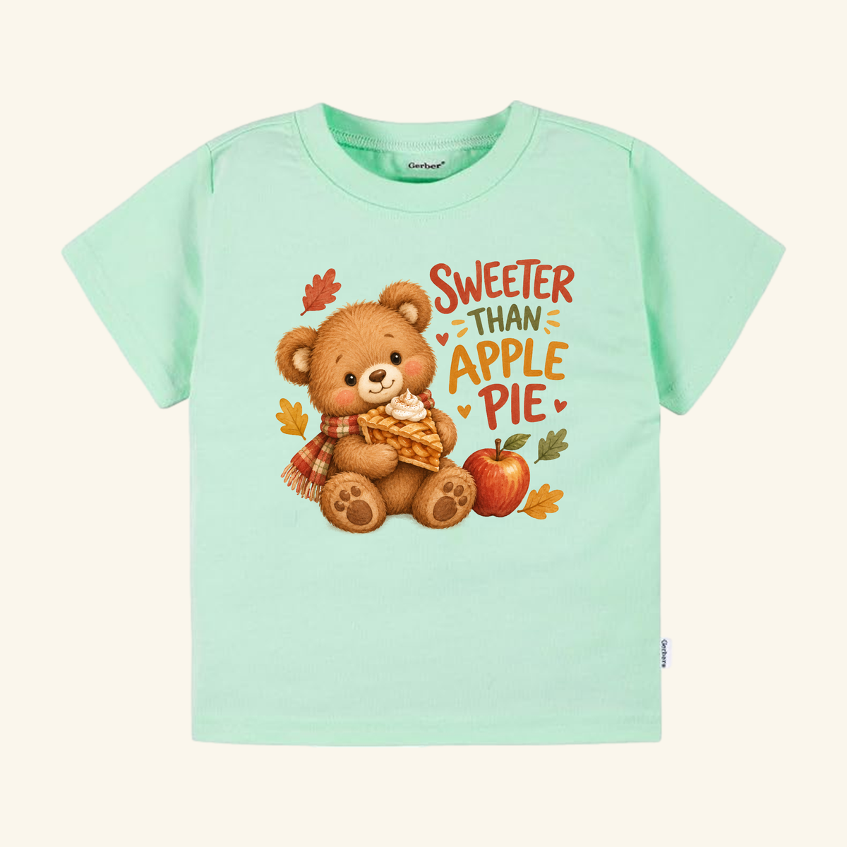 Light green short-sleeve Sweeter Than Apple Pie Toddler Shirt – Fall Bear Short-Sleeve Tee featuring a teddy bear holding a slice of pie, next to an apple and the text Sweeter than apple pie.