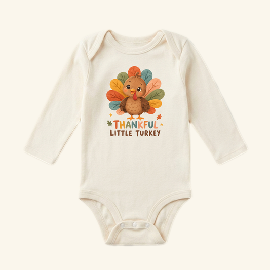 Cream long-sleeve Thankful Little Turkey Baby Onesie – Thanksgiving Bodysuit featuring a cartoon turkey graphic and the text THANKFUL LITTLE TURKEY, perfect as a fall baby outfit.