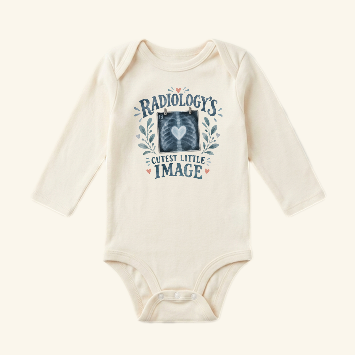 Cream long-sleeved Radiology’s Cutest Little Image Baby Onesie featuring an X-ray heart graphic with floral accents and the text Radiology’s Cutest Little Image.