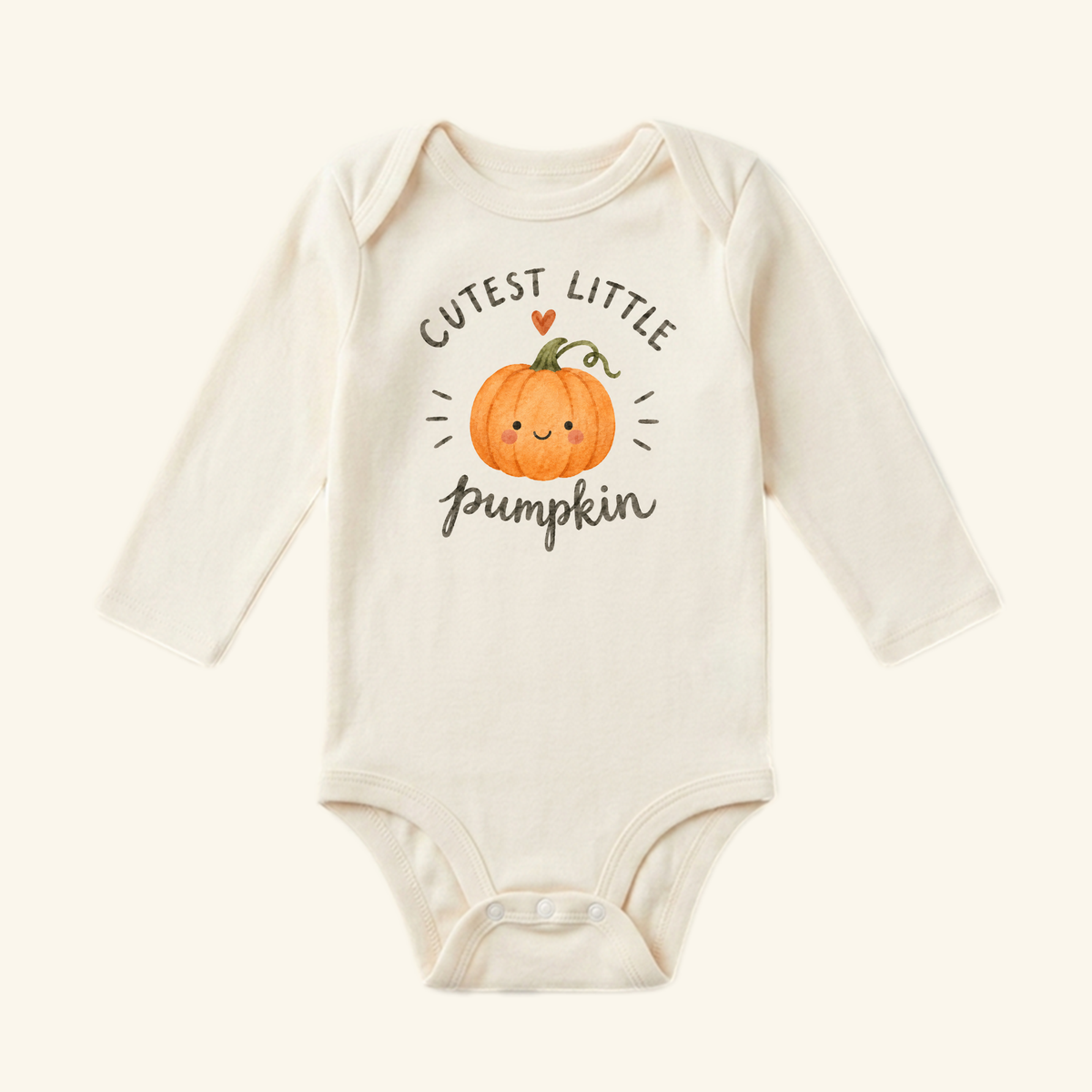 Cream-colored long-sleeve Cutest Little Pumpkin Baby Onesie featuring a smiling pumpkin graphic with a small heart and the text CUTEST LITTLE pumpkin.
