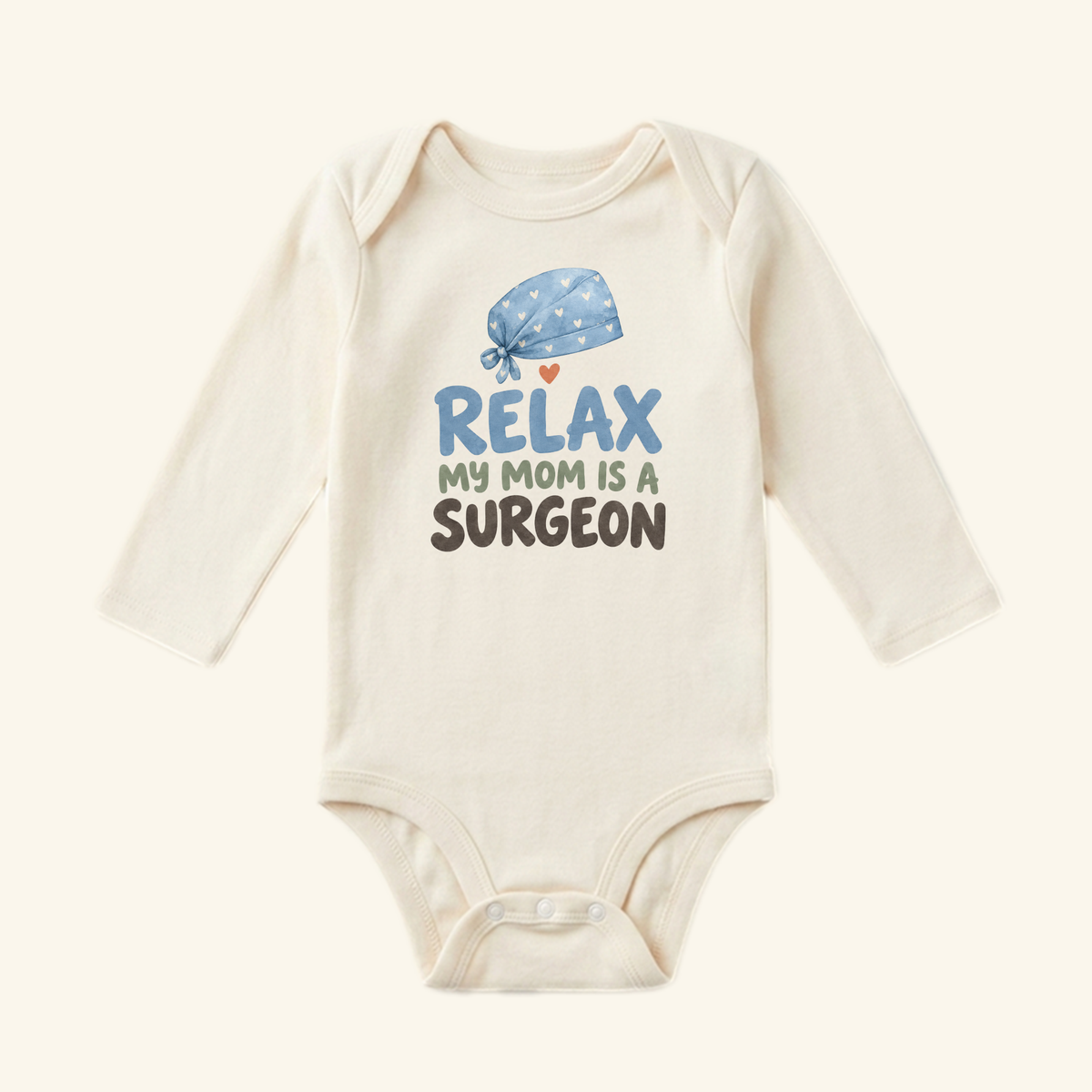 Surgeon Mom Baby Onesie – Relax My Mom Is a Surgeon Bodysuit featuring a long-sleeved white onesie with a graphic of a blue surgical cap with hearts and the text, Relax my mom is a surgeon.