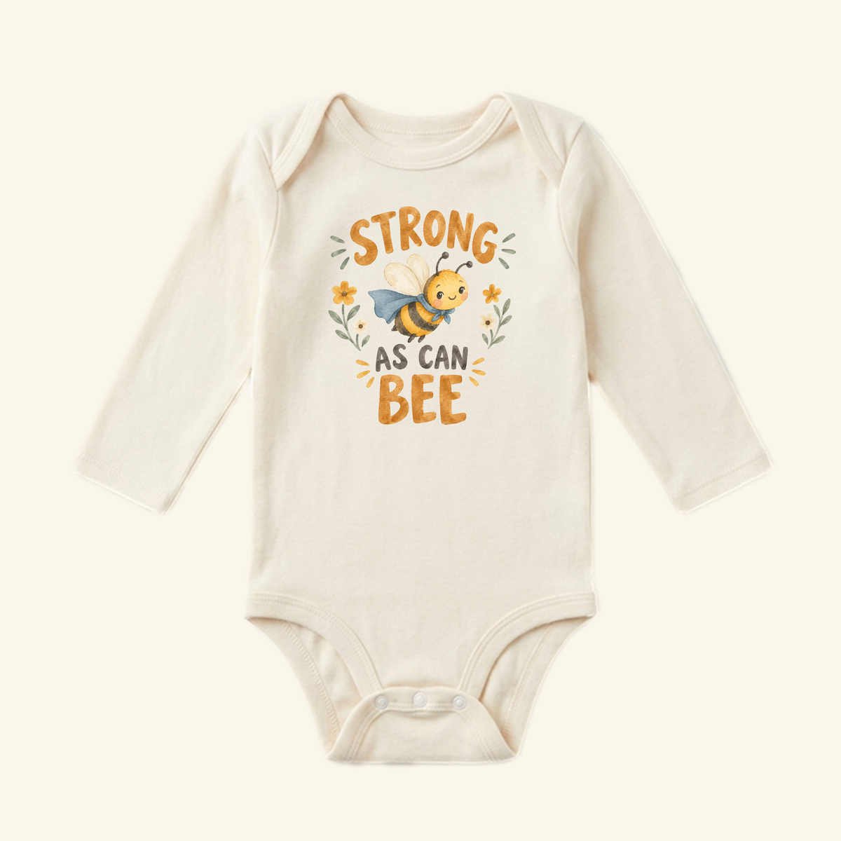 Cream-colored long-sleeve Strong As Can Bee Baby Onesie – Superhero Bee Bodysuit featuring a cartoon bee in a cape, surrounded by floral accents.