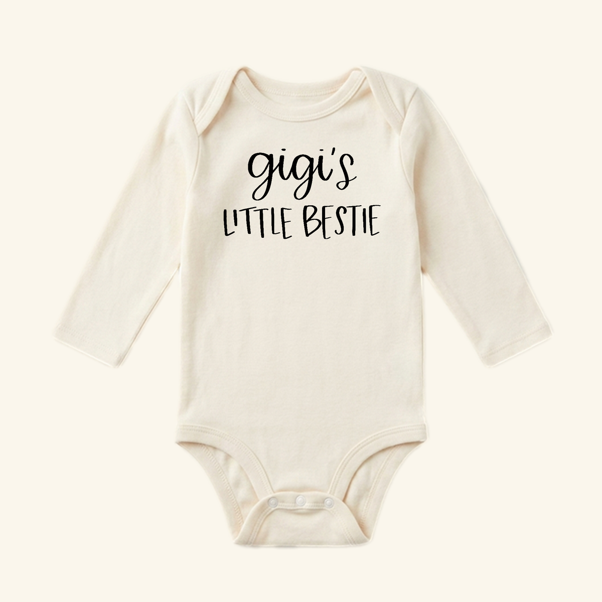 Cream-colored long-sleeve Gigi Baby Onesie – Gigi’s Little Bestie Bodysuit with the text printed in black on the chest.