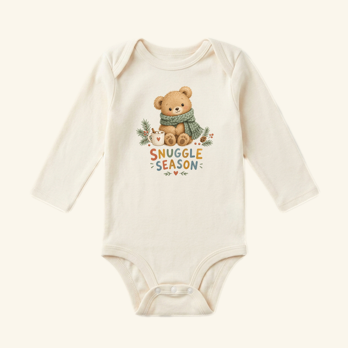 Cream-colored long-sleeve Snuggle Season Baby Onesie – Cozy Winter Teddy Bear Bodysuit featuring a teddy bear with a green scarf and mug, accompanied by the text SNUGGLE SEASON.