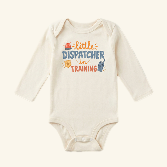 Long-sleeved cream Little Dispatcher in Training Baby Onesie featuring a graphic with a siren, badge, and walkie-talkie icons.