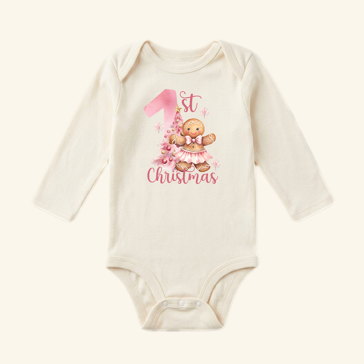 Cream-colored long-sleeve Toodleroos Baby Girl First Christmas Onesie – Gingerbread Holiday Bodysuit featuring a gingerbread girl in a pink tutu next to a Christmas tree and the text 1st Christmas.