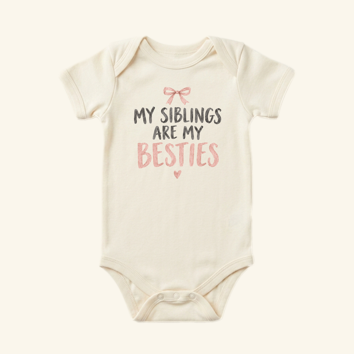 Cream-colored My Siblings Are My Besties Baby Onesie – Pink Bow Sibling Bodysuit featuring a pink bow, a small heart, and the text MY SIBLINGS ARE MY BESTIES.