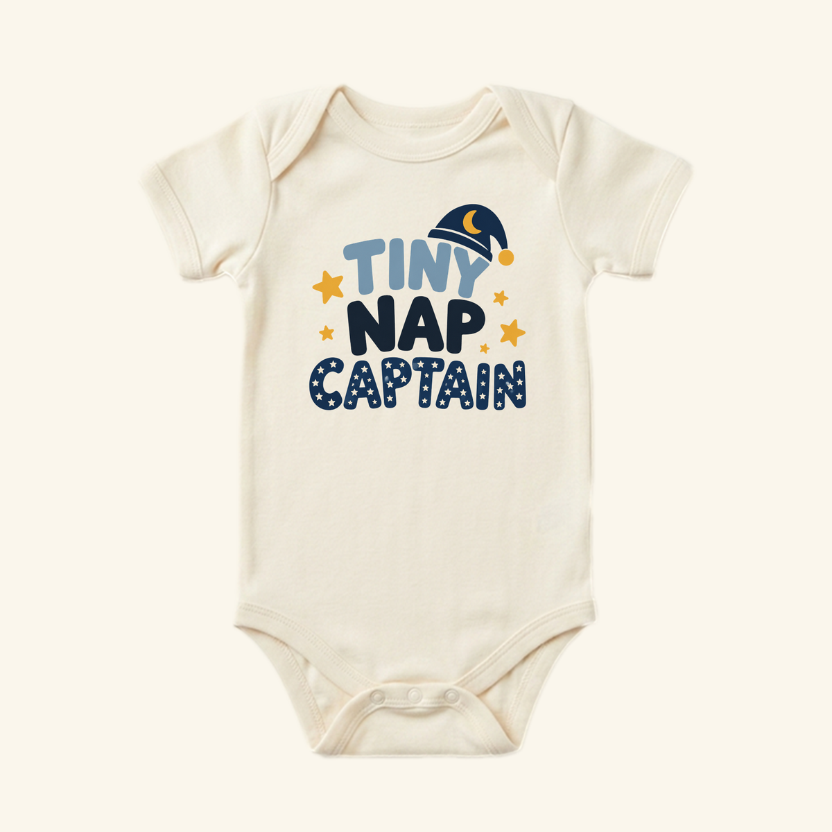 Cream-colored Funny Baby Onesie – Tiny Nap Captain Sleepy Baby Bodysuit decorated with a sleeping cap icon and small stars, making for a charming gender-neutral baby gift.