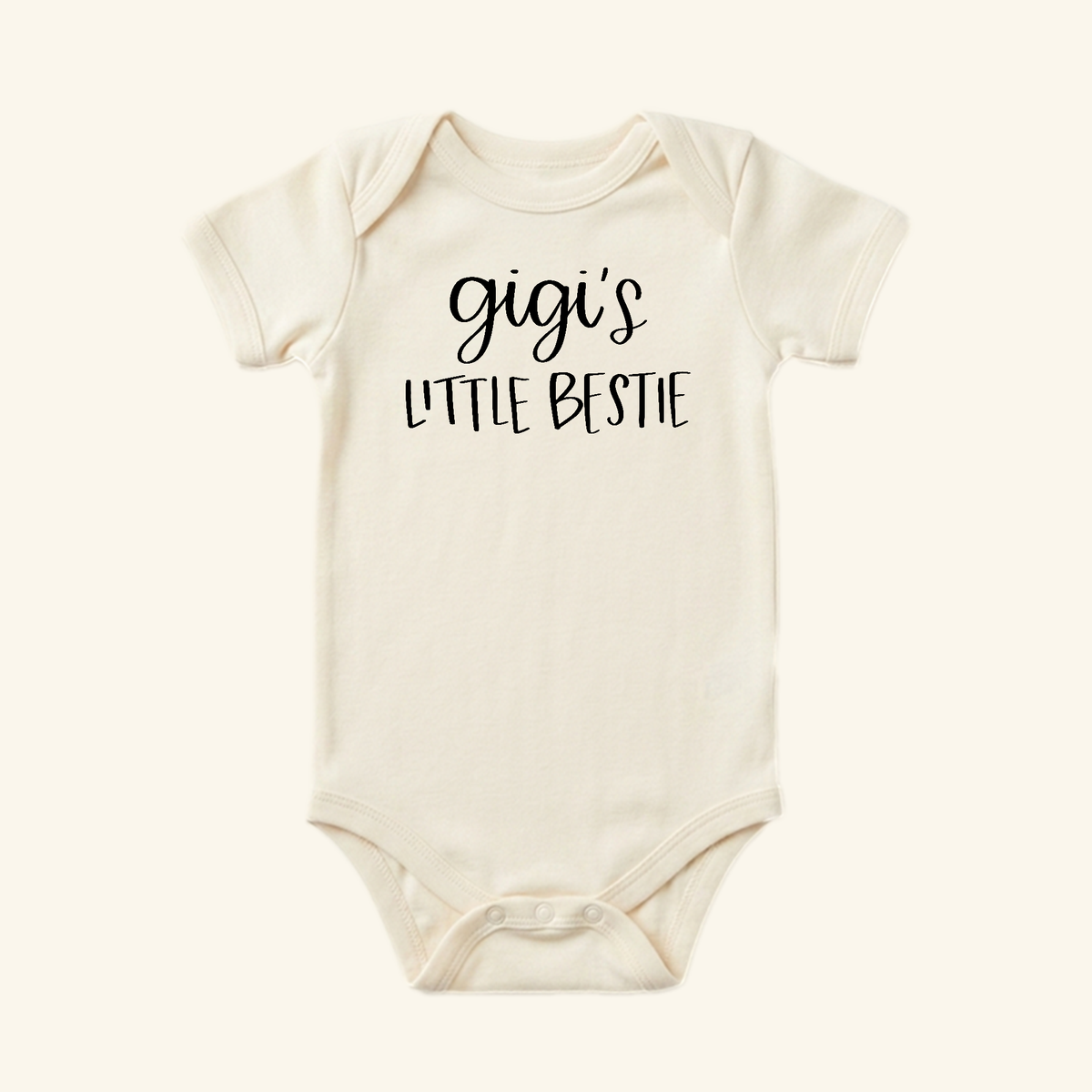 Cream-colored Toodleroos Gigi Baby Onesie – Gigi’s Little Bestie Bodysuit featuring Gigi’s Little Bestie printed in black on the chest.