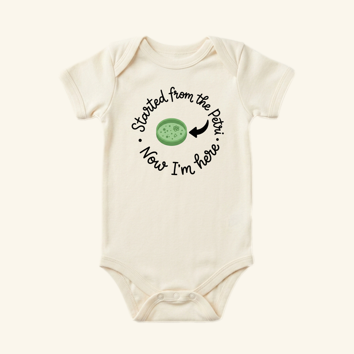 Cream-colored Started From the Petri Baby Onesie – Funny IVF Baby Bodysuit featuring a petri dish graphic and the text, Started from the Petri, Now I’m here.