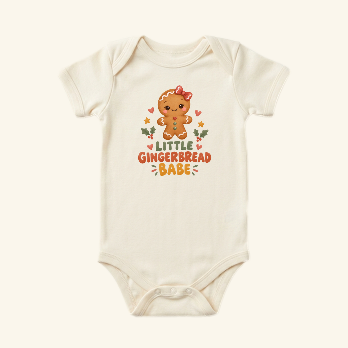 Cream-colored Little Gingerbread Babe Baby Onesie featuring a cartoon gingerbread character, the text Little Gingerbread Babe, and surrounding hearts, stars, and holly leaves.
