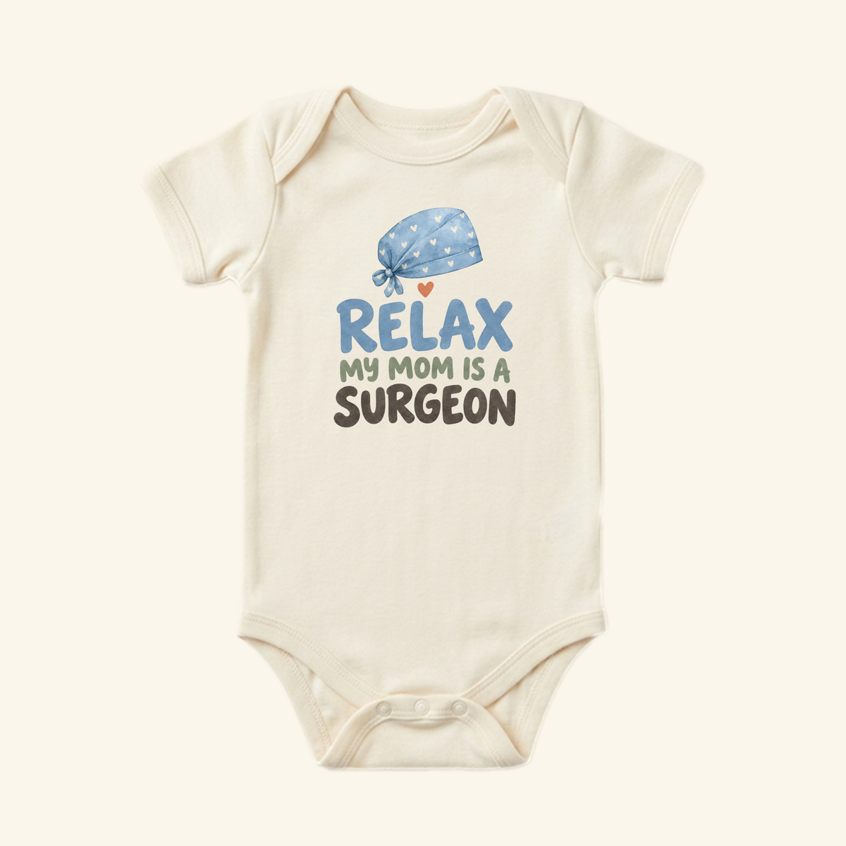 Cream-colored Surgeon Mom Baby Onesie – Relax My Mom Is a Surgeon Bodysuit featuring a blue surgical cap illustration and the text Relax my mom is a surgeon.