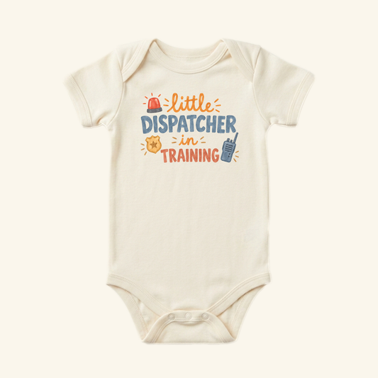 Off-white Little Dispatcher in Training Baby Onesie with the text little DISPATCHER in TRAINING surrounded by icons of a siren, a badge, and a walkie-talkie.