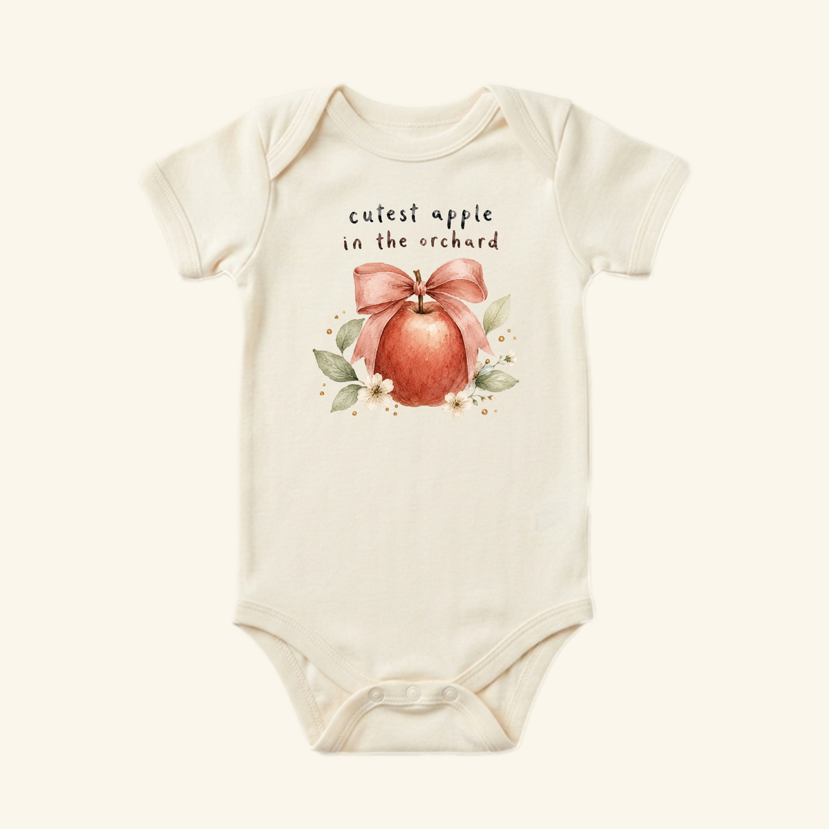Cream-colored Cutest Apple in the Orchard Baby Onesie – Fall Apple Bow Bodysuit featuring a watercolor apple with a pink bow and flowers, with cutest apple in the orchard written above; a charming fall baby outfit for apple picking.