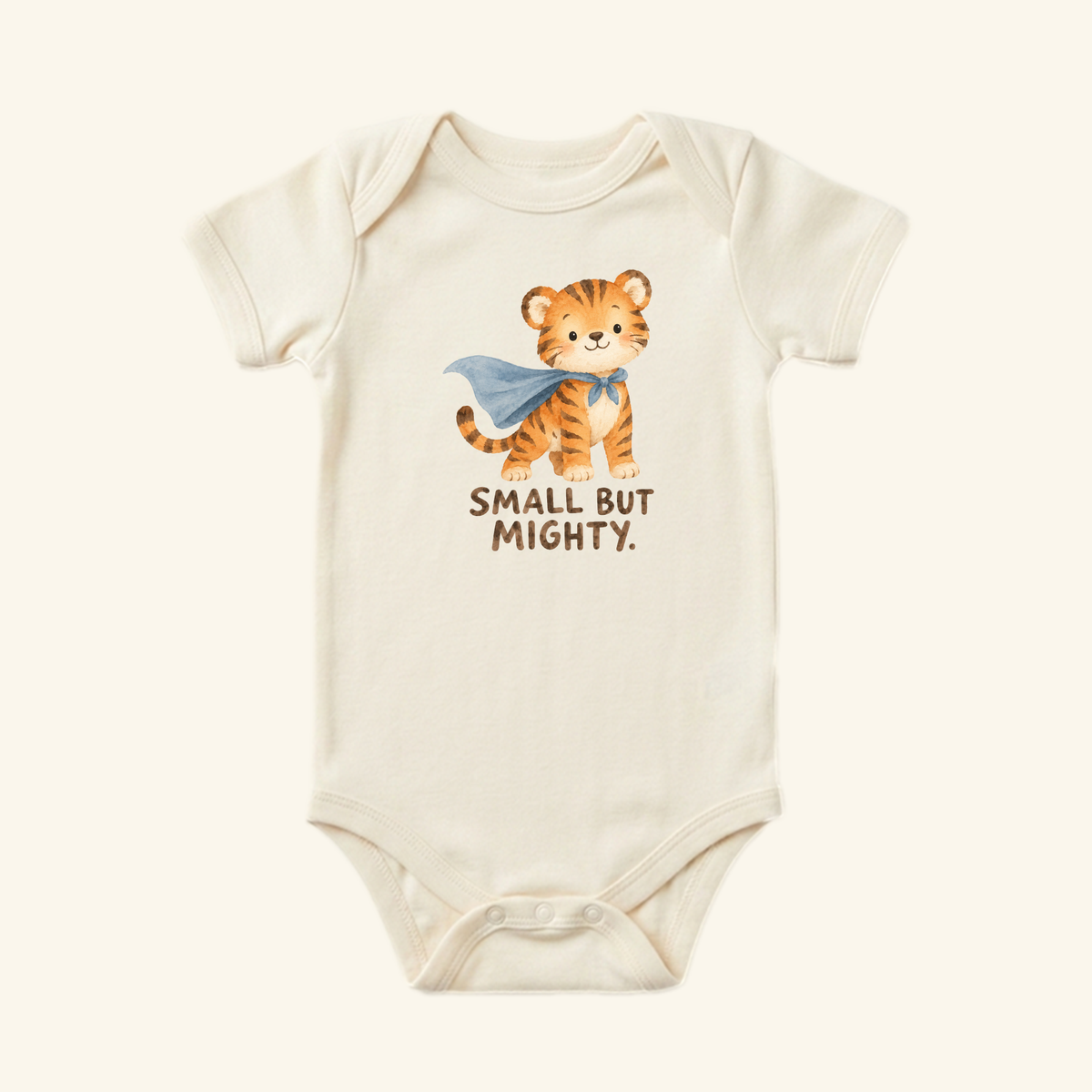 Small But Mighty Baby Onesie – Superhero Tiger Bodysuit in cream, featuring a watercolor illustration of a tiger wearing a blue cape with the text SMALL BUT MIGHTY printed below.