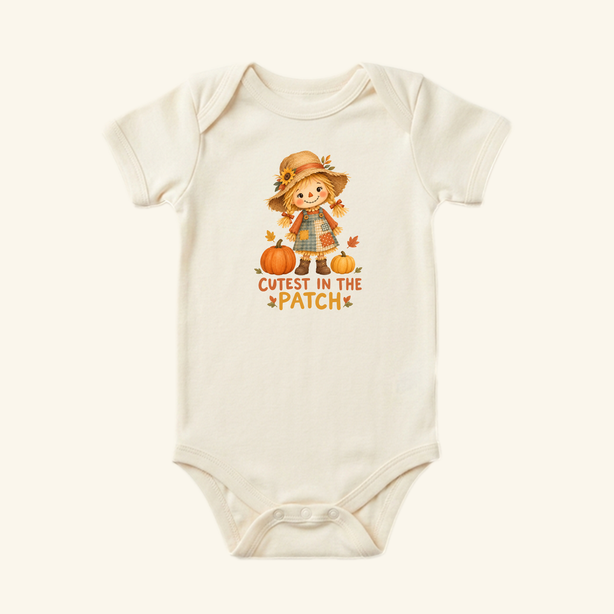 Off-white Cutest in the Patch Baby Onesie – Fall Scarecrow Girl Bodysuit featuring an illustration of a girl scarecrow with two pumpkins and the text CUTEST IN THE PATCH.