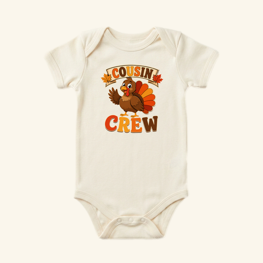 Cream-colored Thanksgiving Cousin Baby Onesie – Cousin Crew Turkey Bodysuit featuring a cartoon turkey waving, autumn leaves, and the text COUSIN CREW.