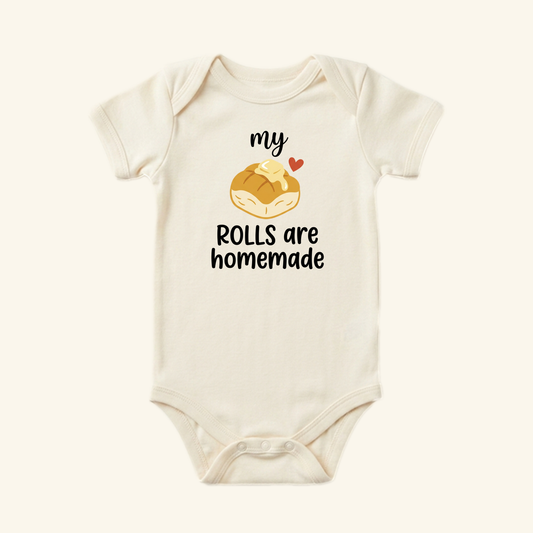 Cream-colored My Rolls Are Homemade Baby Thanksgiving Onesie - Fall Bodysuit featuring an illustration of a dinner roll with a pat of butter and the text my ROLLS are homemade.