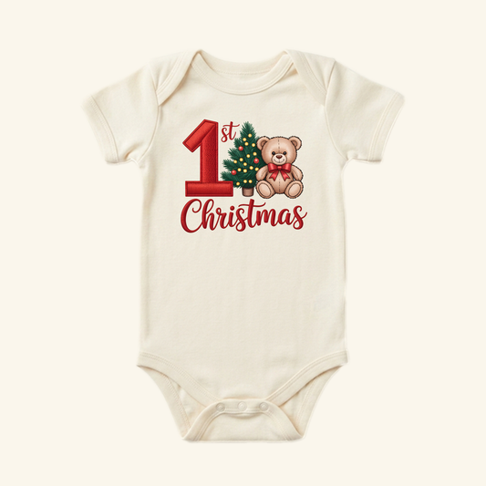 Cream-colored Baby’s First Christmas Onesie – Teddy Bear & Christmas Tree Bodysuit featuring a graphic of a teddy bear, a Christmas tree, and the text 1st Christmas.