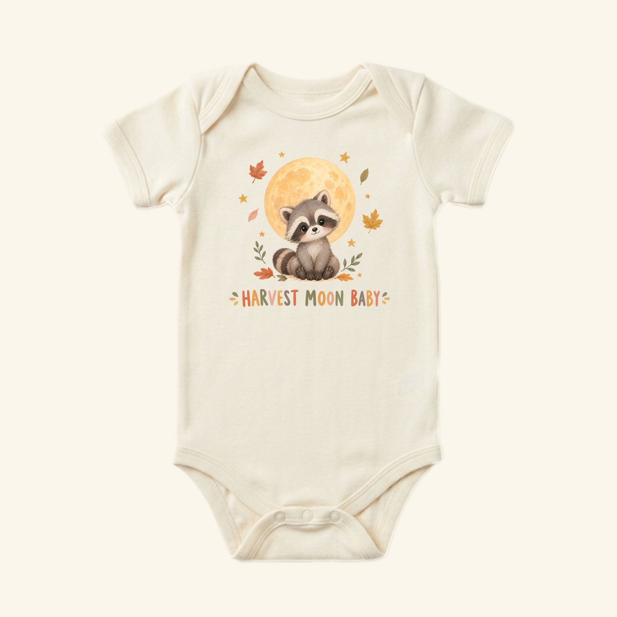 Cream-colored Harvest Moon Baby Onesie – Fall Raccoon Bodysuit featuring a raccoon sitting in front of a full moon, surrounded by autumn leaves and the text Harvest Moon Baby.
