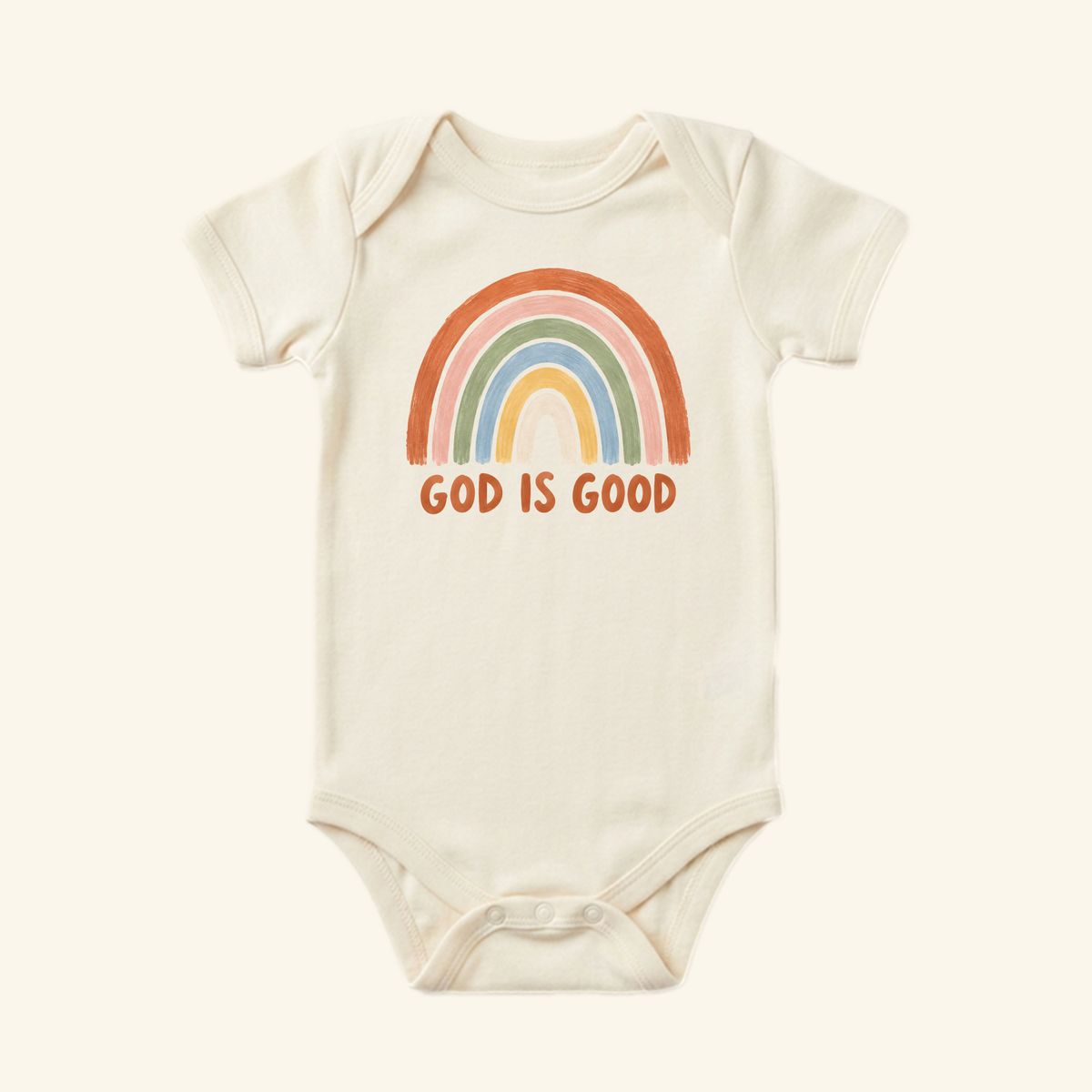 The Toodleroos Christian Baby Onesie – God Is Good Rainbow Bodysuit is cream-colored with a muted rainbow and bold orange GOD IS GOOD text—an ideal Christian baby gift.
