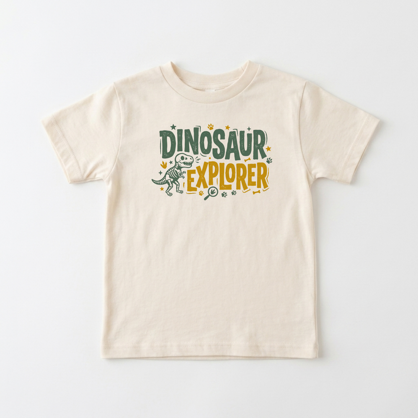 A light beige short-sleeve t-shirt with a 'Dinosaur Explorer' graphic on the chest, featuring a small dinosaur illustration and colorful text, displayed on a clean white background.