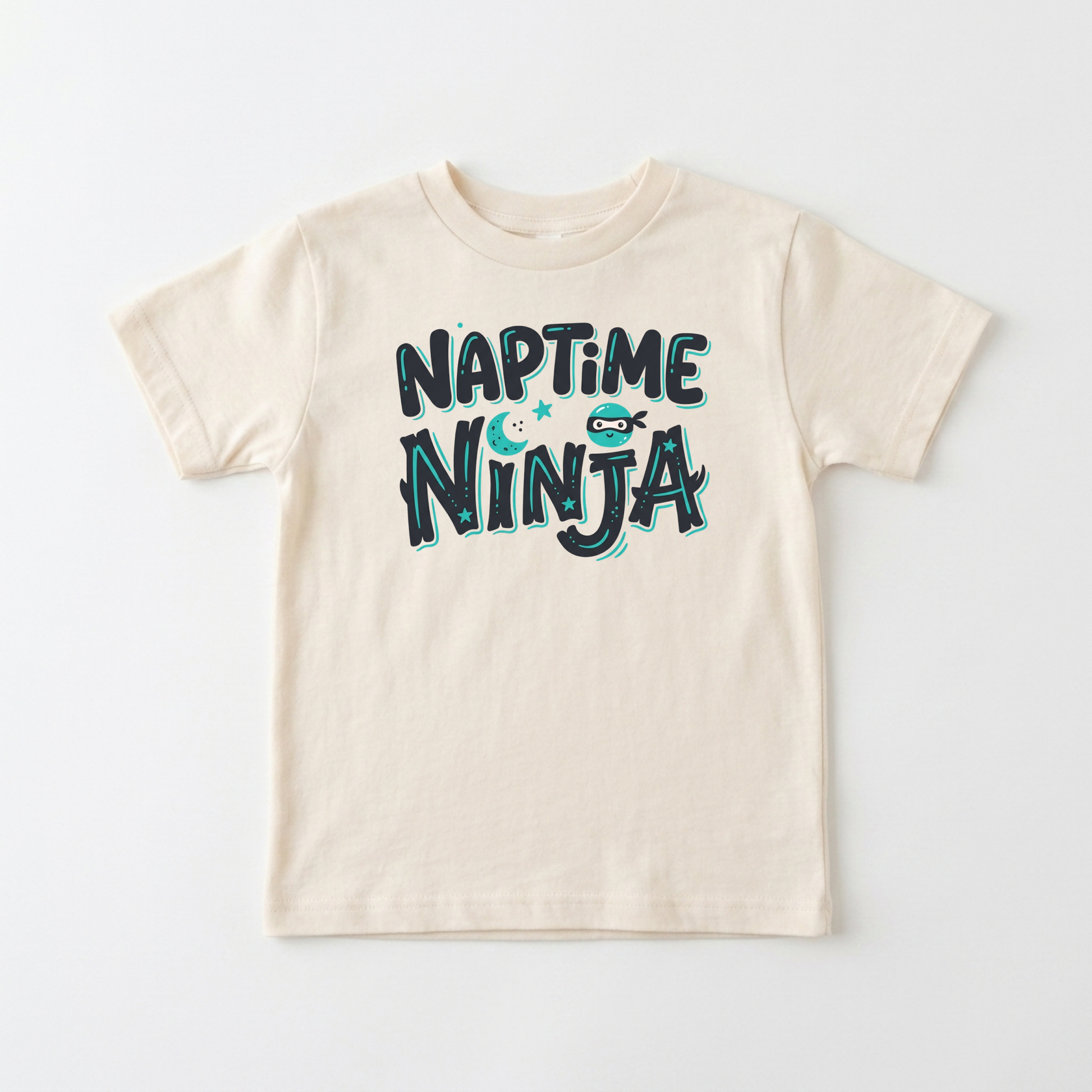 A cream-colored short-sleeve kids' t-shirt with a 'NAPTIME NINJA' graphic printed on the chest in dark teal and light blue, laid flat against a light gray background.