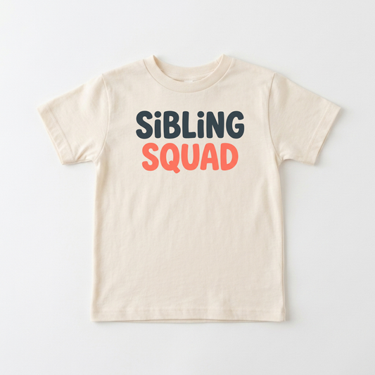 A cream-colored short-sleeve t-shirt with the text 'SiBLING SQUAD' printed on the chest. 'SiBLING' is in dark navy blue letters, and 'SQUAD' is in coral orange.